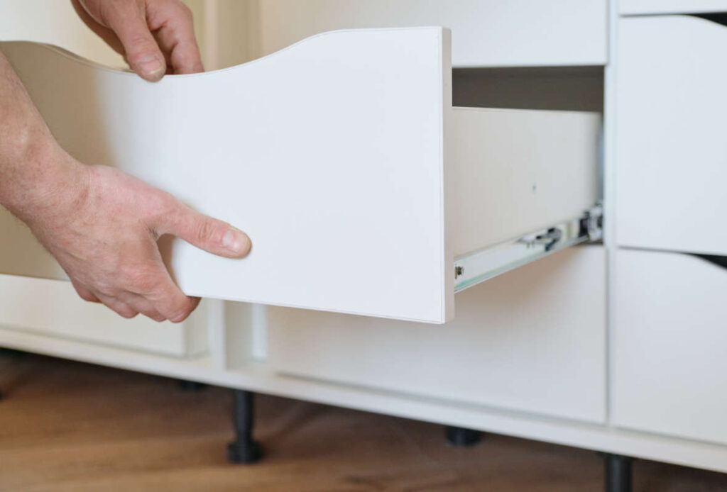 Person sliding drawer into dresser