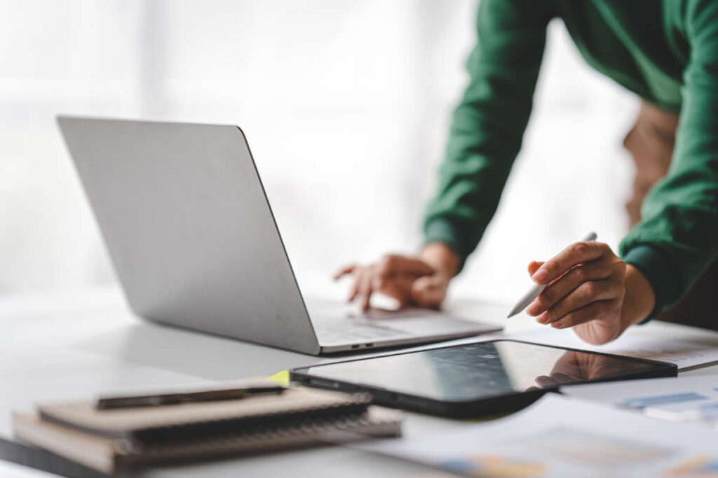 Person typing on laptop while also utilizing Ipad.