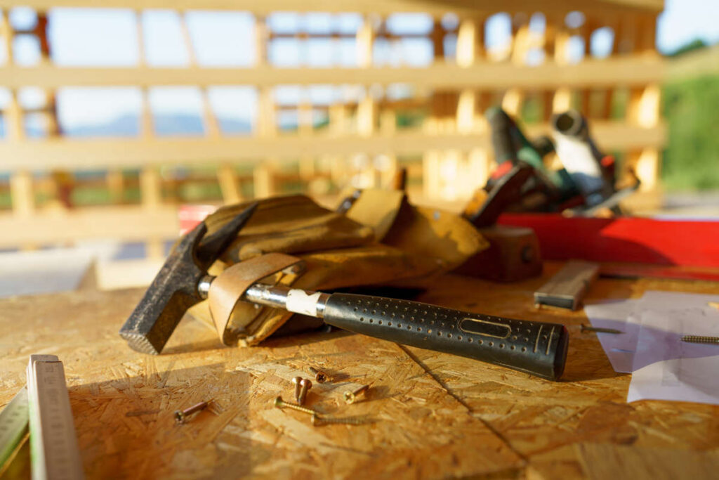 Hammer laying on top of material board outside in unfinished house frame
